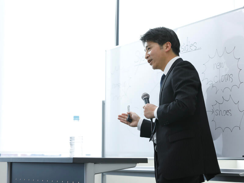 スーツをきた男性がセミナーをしている写真